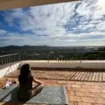 woman on yoga mat reflectively looking into scenic view at psilocybin facilitation training retreat