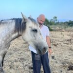 a man in his 50s connecting with a grey horse during equine therapy connection. led by Intuitive Kasham
